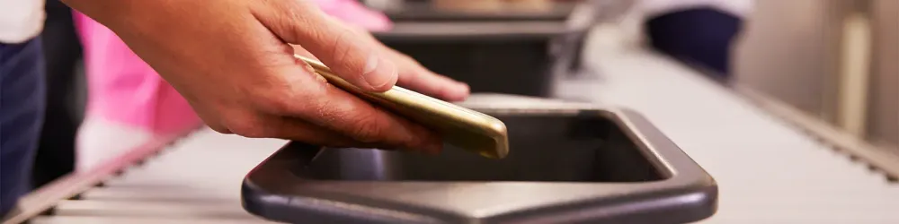 Person placing phone in bin for TSA airport security screening